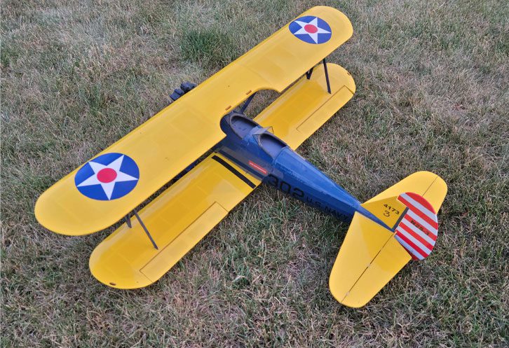 A yellow and blue plane is on the grass