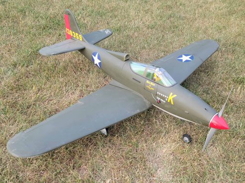 A small model airplane is sitting in the grass.