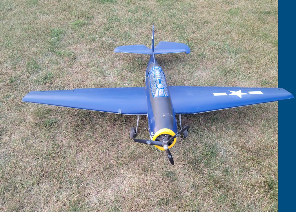 A blue airplane is sitting in the grass.